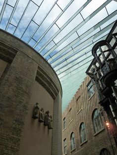 two buildings with glass roofs and statues on them