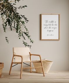 a white chair sitting next to a plant in front of a framed poster on the wall