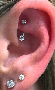 a woman's ear with three diamond studs