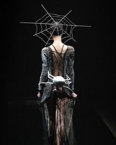 a woman is walking down the runway wearing a costume with spider webs on it