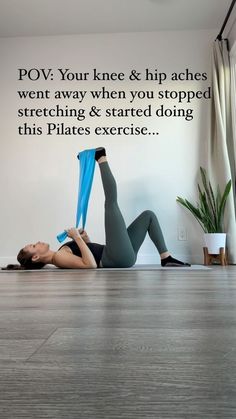 a woman is doing an exercise on the floor with her legs spread out and holding a blue yoga mat