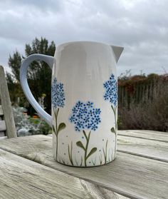 a blue and white pitcher sitting on top of a wooden table next to a bench