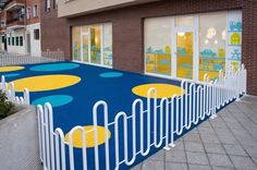 an outdoor play area with yellow and blue circles on the ground next to a brick building