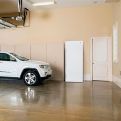 a white jeep parked in a garage next to a tall refrigerator freezer and door