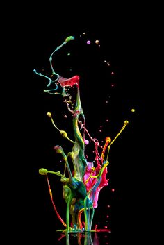 colorful paint splashing into the water on a black background