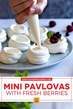 mini pavlovas with fresh berries being drizzled over them on a plate