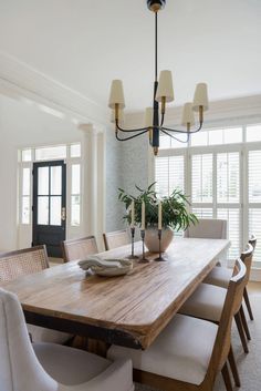 a dining room table with white chairs and a potted plant on top of it