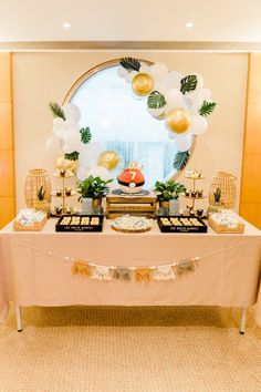 the table is set up with balloons, plates and desserts in front of it