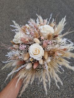 a person holding a bouquet with flowers on the ground in front of their hand,