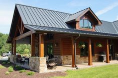 a large wooden house with metal roofing and stone pillars on the front porch area