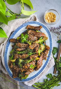 beef and broccoli stir fry on a plate with chopsticks next to it