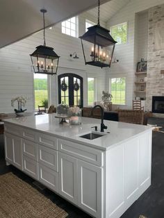 a large kitchen with an island in the middle and two lights hanging from the ceiling