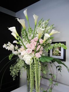 a vase filled with white and pink flowers on top of a counter next to a mirror