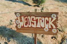 a wooden sign sitting on top of a dirt field