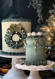 two cakes decorated with wreaths and decorations on top of each other, sitting next to a christmas tree