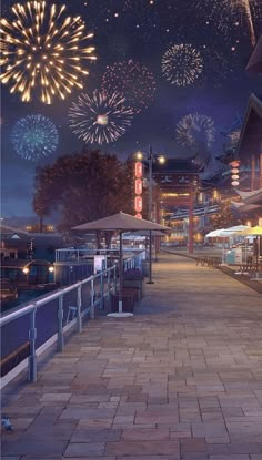 fireworks are lit up in the night sky over a boardwalk with tables and umbrellas