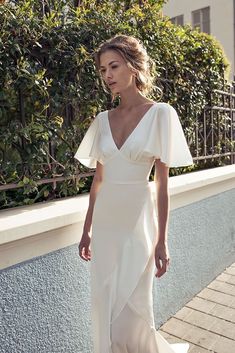 a woman in a white dress is standing outside