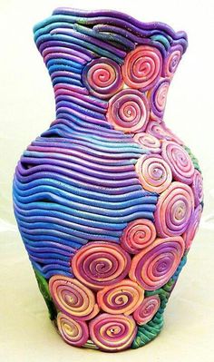 a colorful vase sitting on top of a white table covered in swirls and leaves