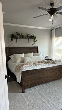 a bedroom with a bed, ceiling fan and two planters on the windowsill