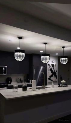 a kitchen with an island and lights hanging from the ceiling