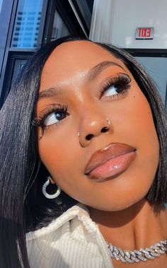 a close up of a person wearing a necklace and earrings with her eyes closed to the camera