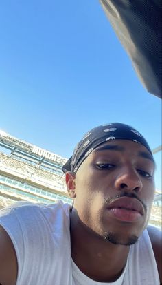 a man with a bandana on sitting in front of an empty bleachers