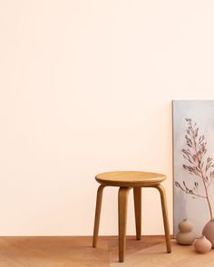 a small wooden stool next to a painting and vases on the floor in front of it