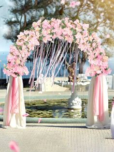 a wedding arch decorated with pink flowers and streamers