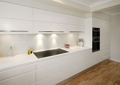 a modern kitchen with white cabinets and wood flooring