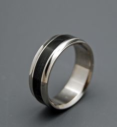 a silver ring with black and white stripes on the inside, sitting on a gray surface