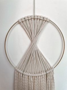 a macrame hanging on a white wall with a circular object in the middle