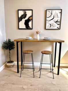 two stools sitting at a table in front of paintings