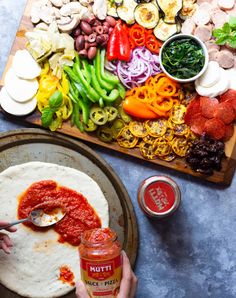 a person dipping sauce on top of a tortilla with peppers, mushrooms and other ingredients