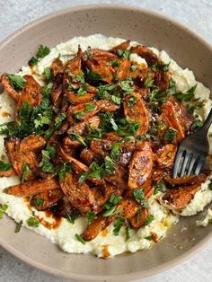 a bowl filled with mashed potatoes topped with meat and garnish