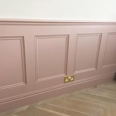 a cat is sitting on the floor in front of a pink paneled wall with gold hardware