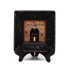 a small black frame with an image of a house and stars on the front, saying live laugh love