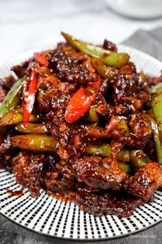 a white plate topped with meat and veggies covered in sauce on top of a table