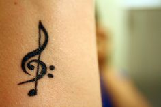 a small black musical note tattoo on the arm