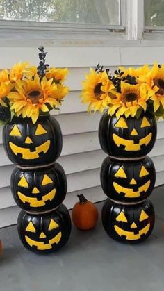 two black pumpkin vases with sunflowers on them