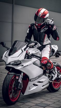 a man in white and red riding on the back of a silver motorcycle wearing a helmet