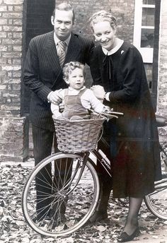 an old black and white photo of two people with a child on a bicycle