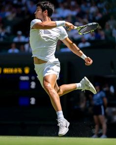 a man in white shirt and shorts playing tennis on a court with people watching from the stands