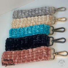 four different color knitted key fobs with metal clip holders on each side