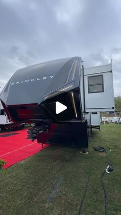 an rv is parked on a red carpet in front of a white and black trailer