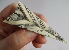 a person holding an origami airplane made out of one dollar bill