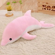 a pink dolphin stuffed animal laying on top of a white rug