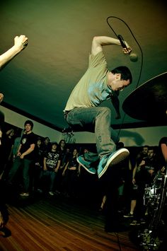 a man is jumping in the air on his skateboard while people watch from behind him