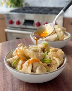 two bowls filled with dumplings and sauce being drizzled over them