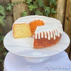 a bundt cake with white icing sitting on a plate next to a fence