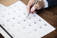 a person writing on a calendar with a pen